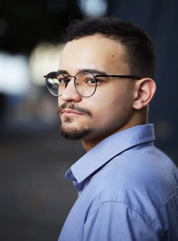 Foto de Vinicius Saraiva, de óculos e camisa social azul-clara.